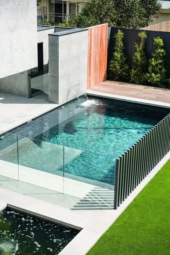 Frameless glass pool safety barrier with stainless steel spigots around a residential swimming pool.