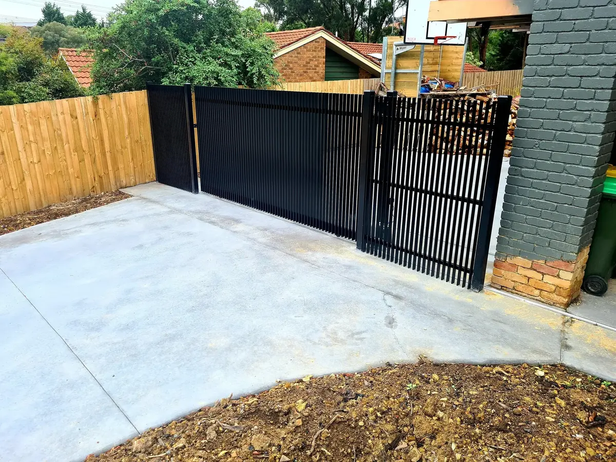 Custom matte black automated sliding driveway gate and matching vertical steel picket front feature fence installed at a residential property in Bundoora.